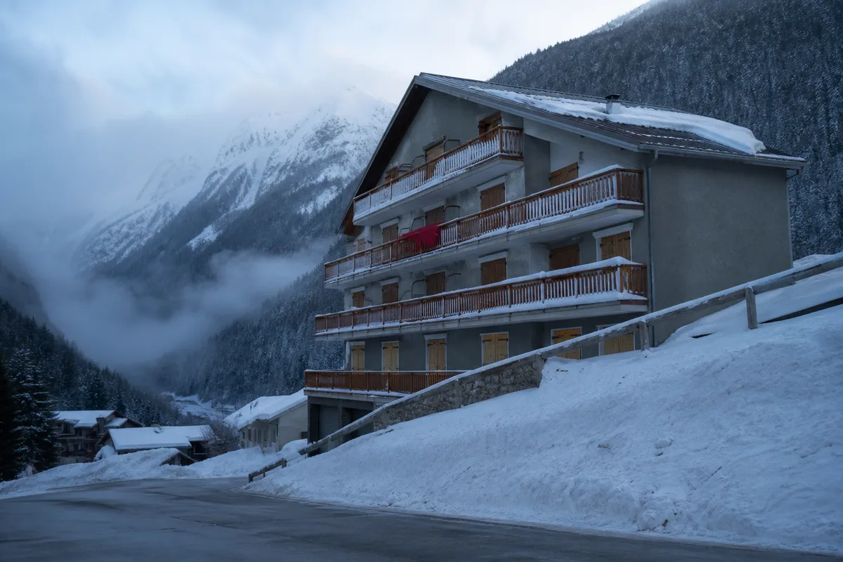 Immeuble de station à Chamonix sous la neige, balcons de bois et façade grise en fin de journée d’hiver
