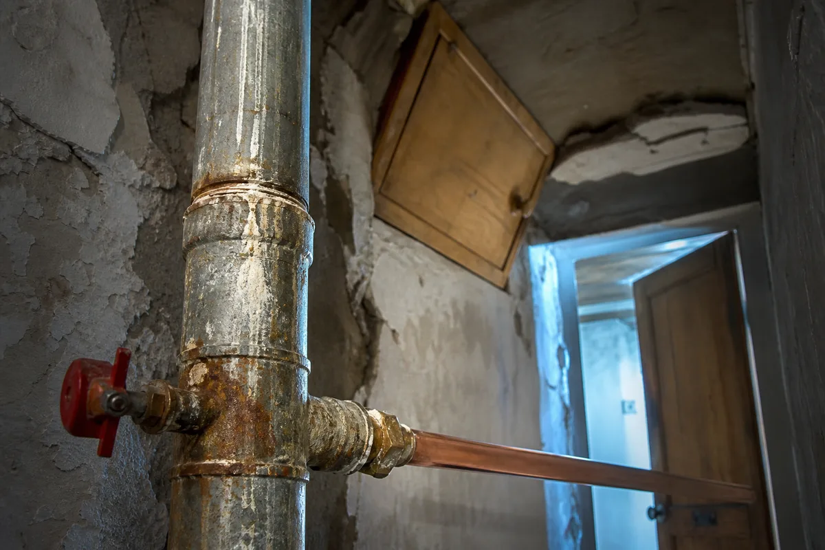 Colonne montante en acier galvanisé corrodée dans la gaine technique d&rsquo;un immeuble ancien de Sallanches